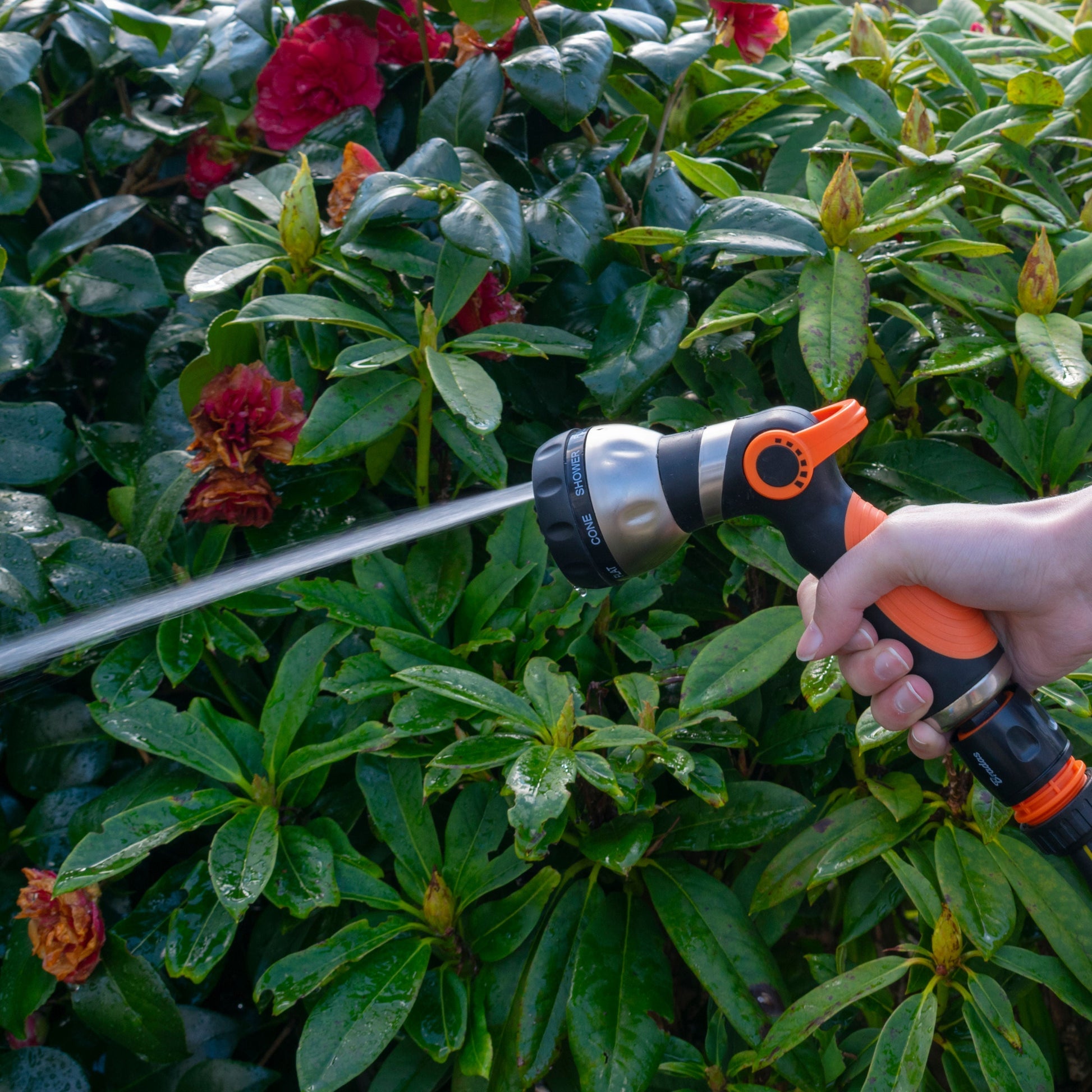 Black and orange sprayer gun with long trigger handle spraying a steady stream