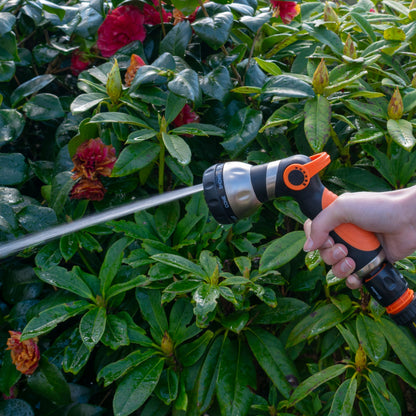 Black and orange sprayer gun with long trigger handle spraying a steady stream
