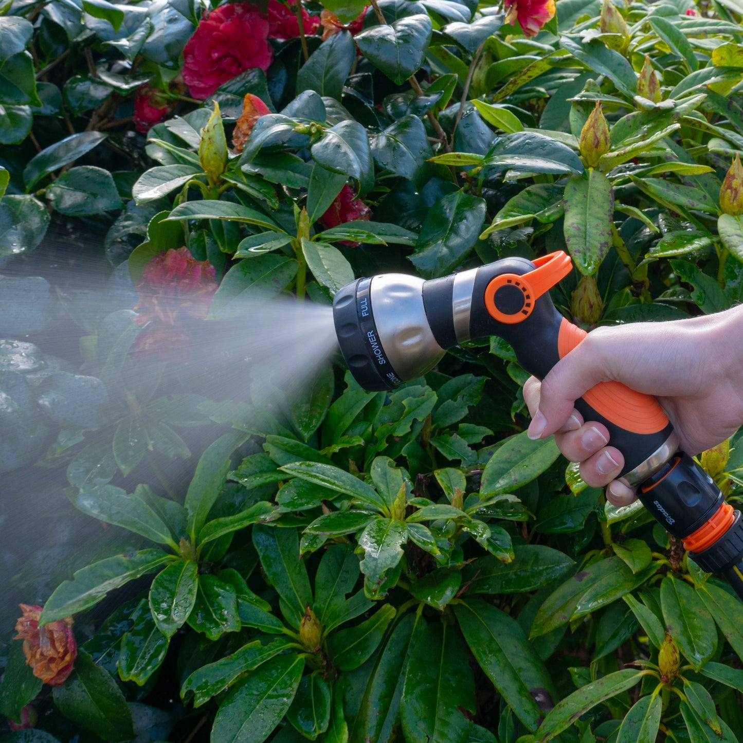 Hose sprayer gun releasing a fine mist from the orange nozzle head
