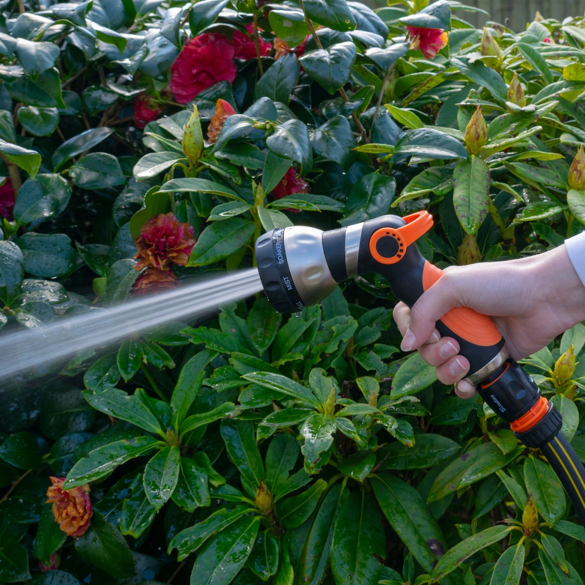 Orange and black hose sprayer gun spraying water with a narrow stream
