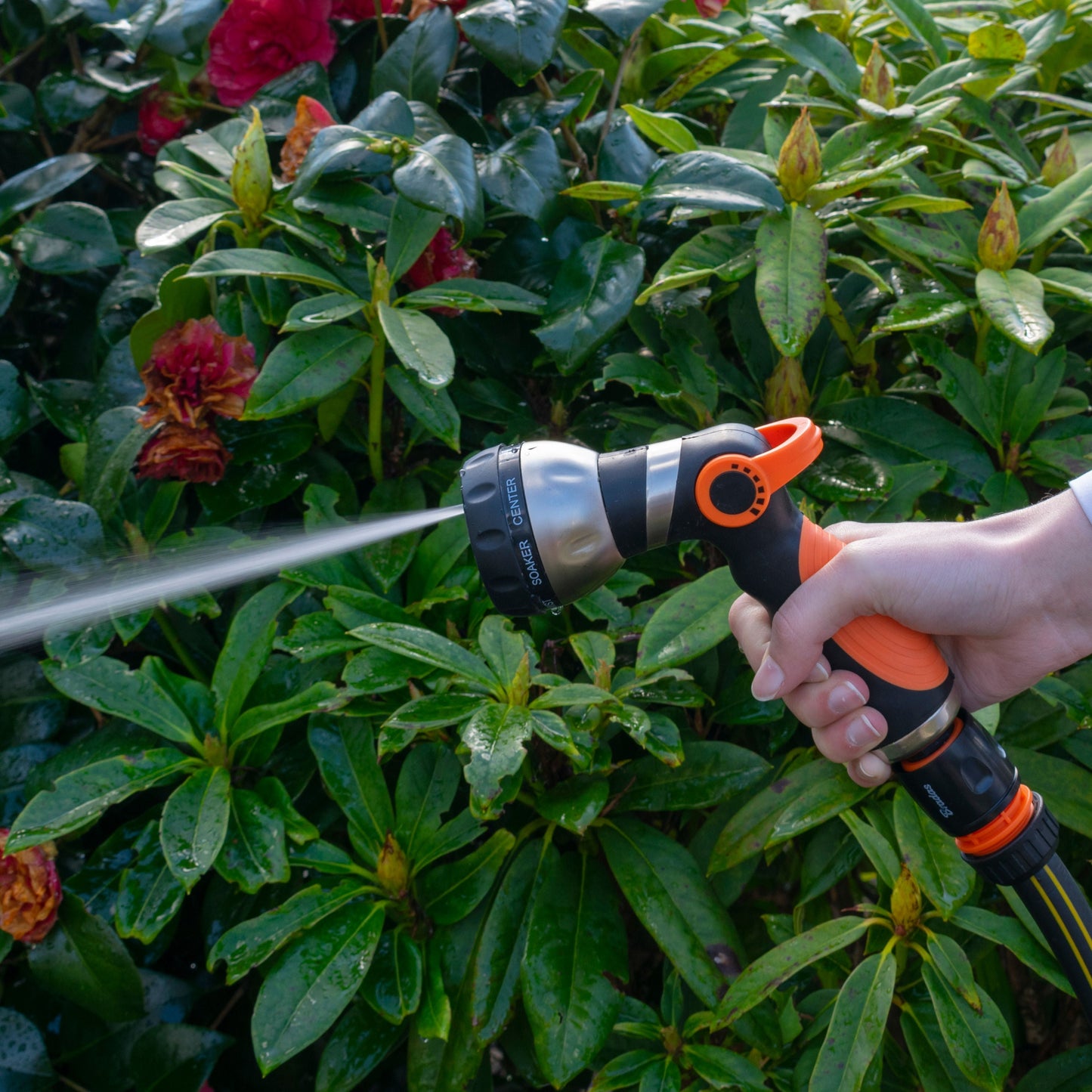 Sprayer gun with orange nozzle head spraying a light mist pattern