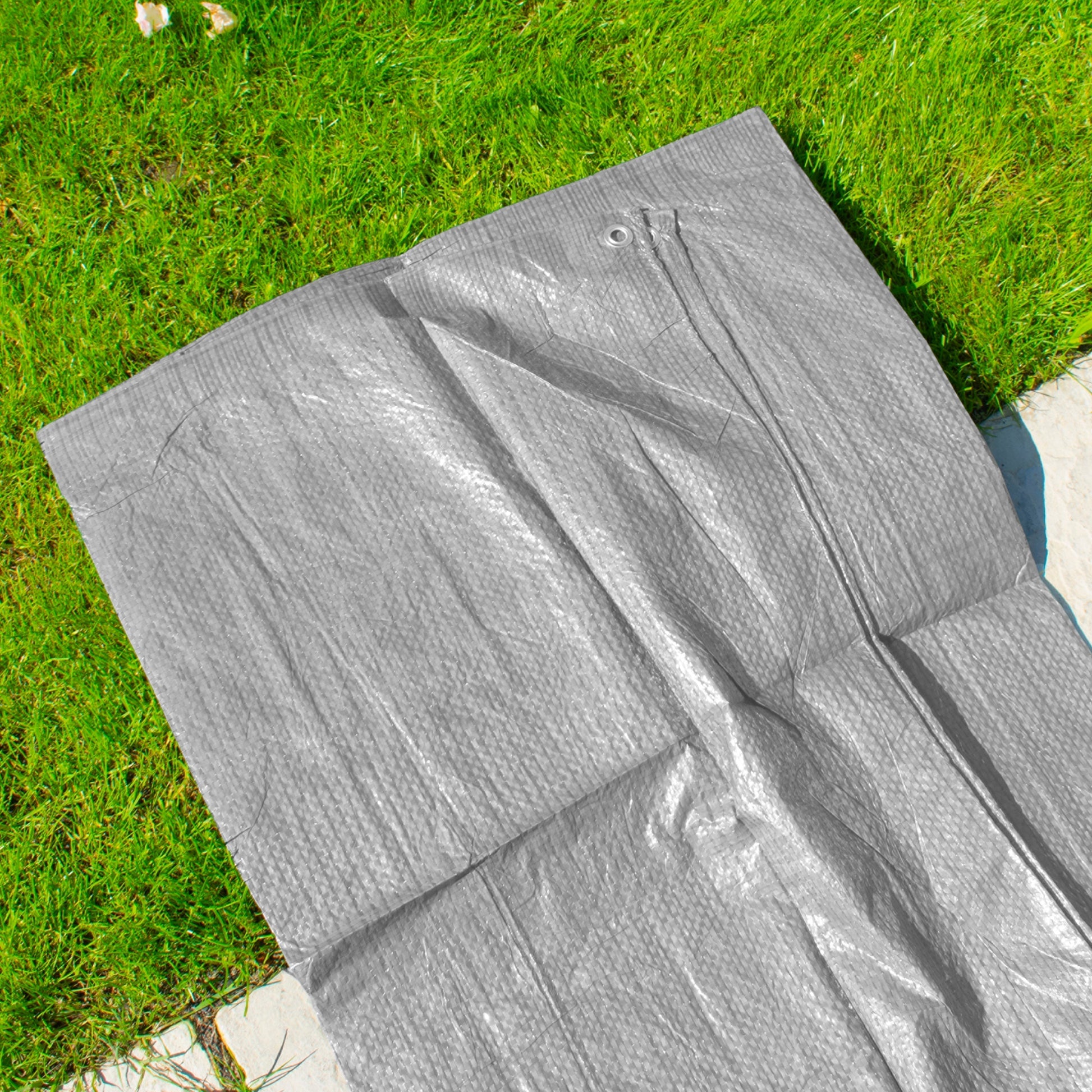 Gray tarpaulin close-up with crinkled surface and small metal eyelet near the top