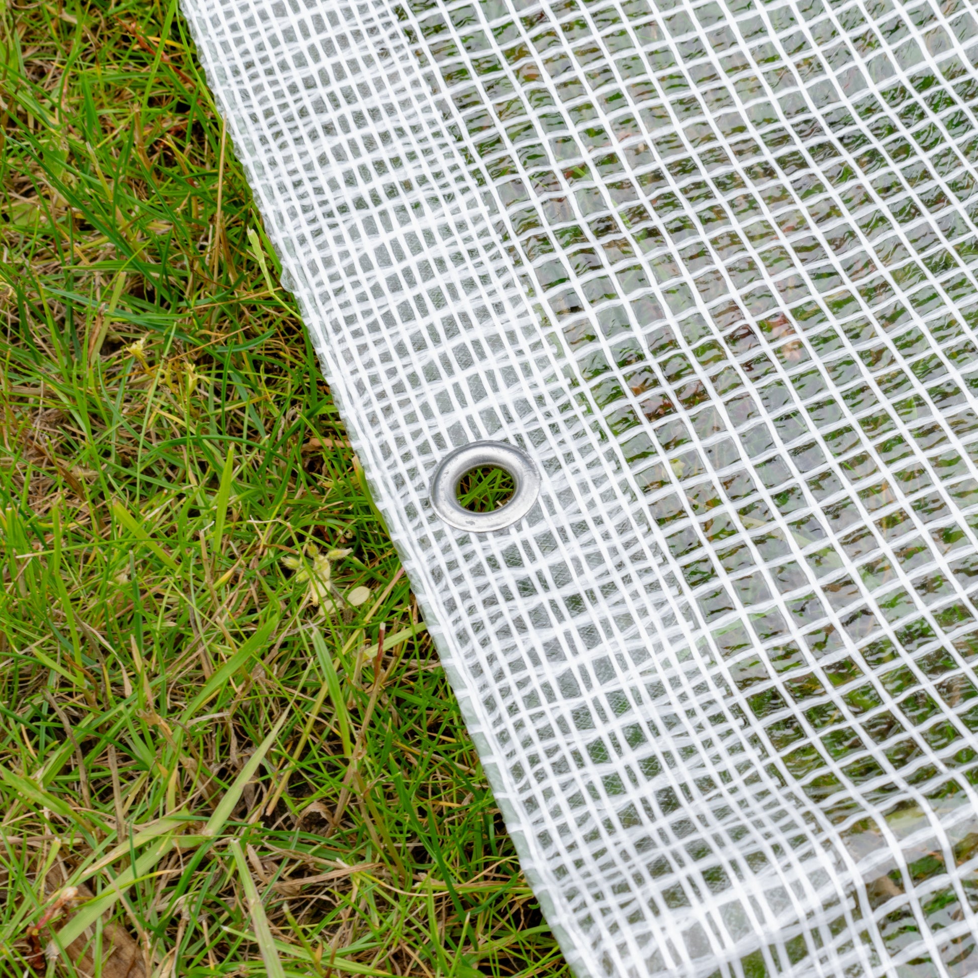 Clear tarpaulin edge with round metal grommet eyelet on reinforced grid