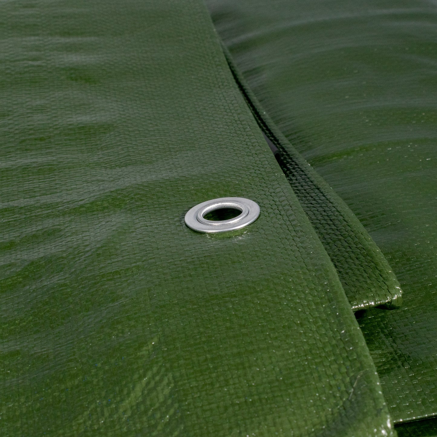 Close-up of green tarpaulin fabric with stitched seam and metal grommet
