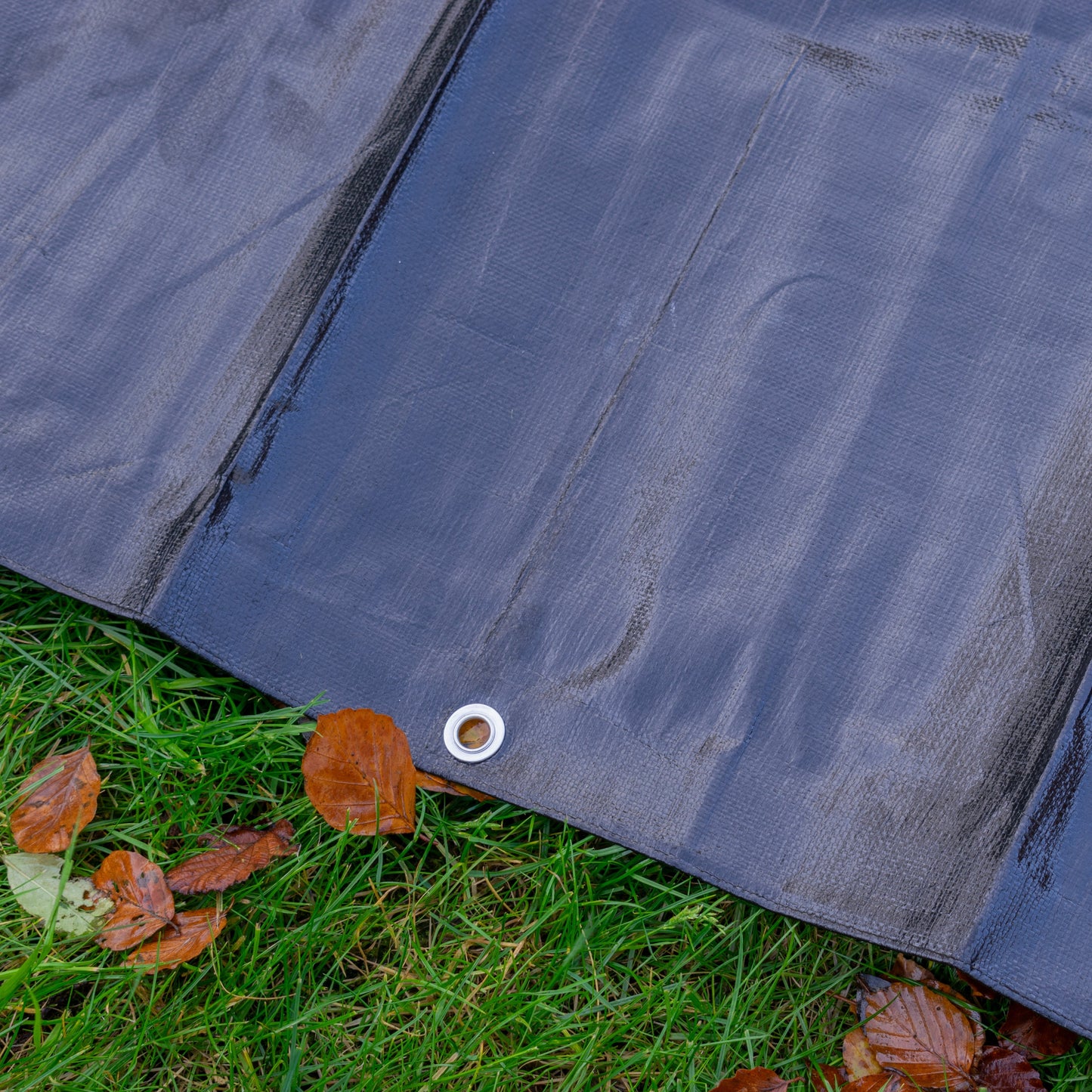 Close-up of black tarpaulin edge with silver grommet on hem