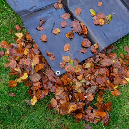 Black tarpaulin corner with silver eyelets, lying among fallen leaves