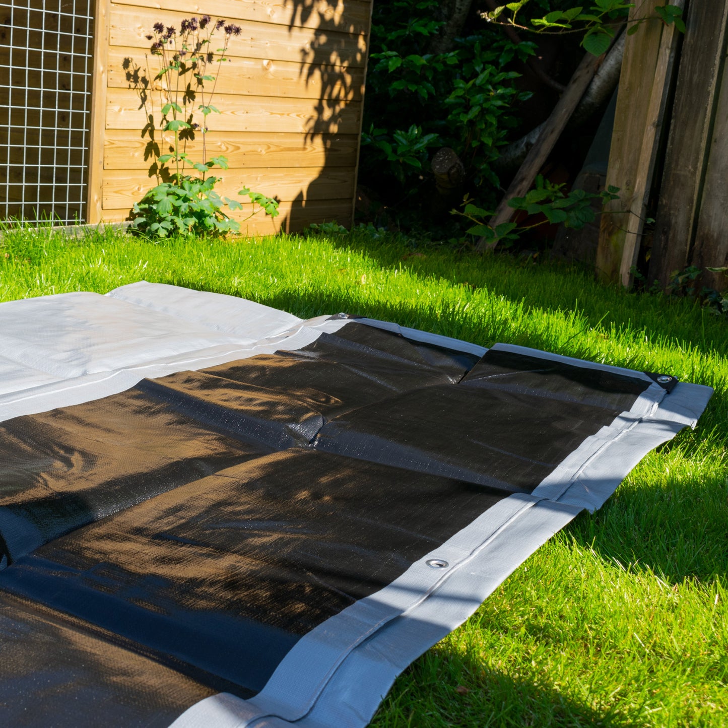 Silver tarpaulin laid flat with reinforced edges and stitched border seams