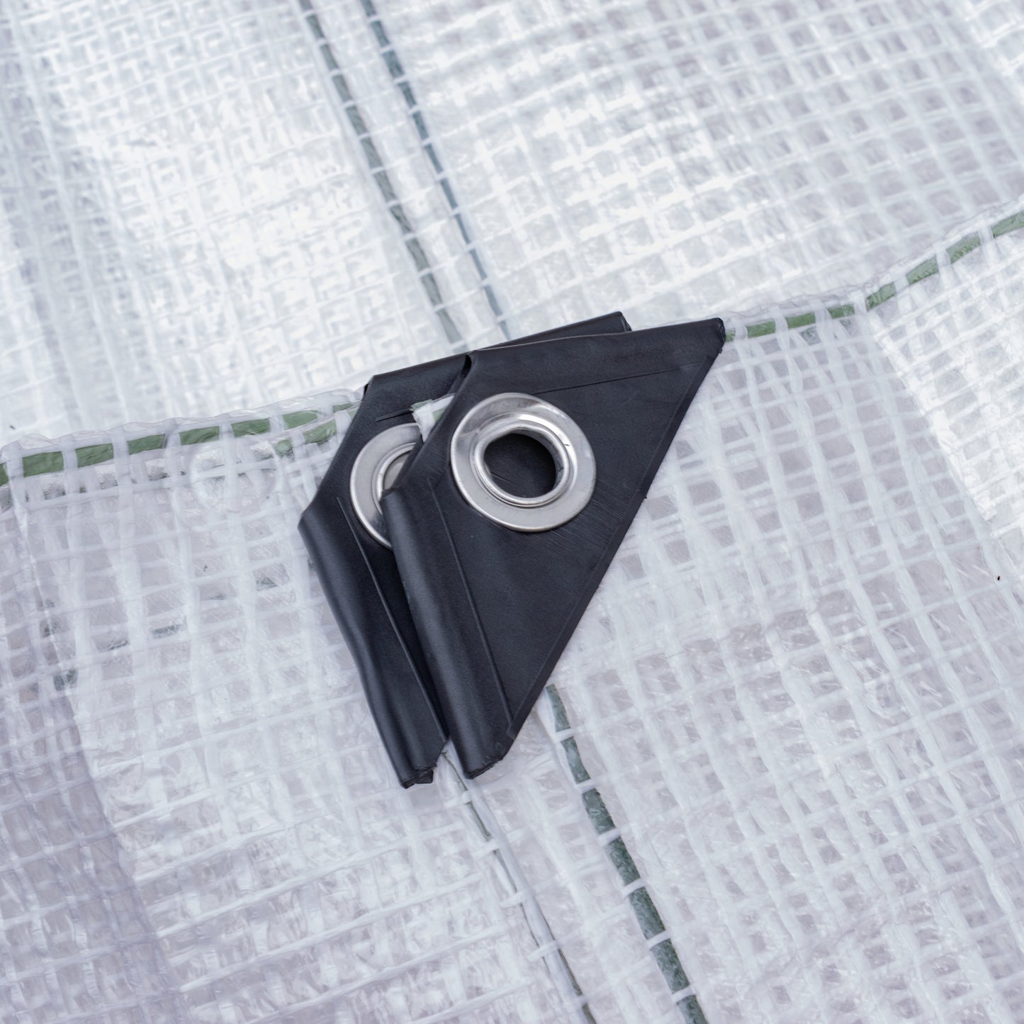 Screw tarp clip attached to clear tarpaulin fabric with metal eyelet
