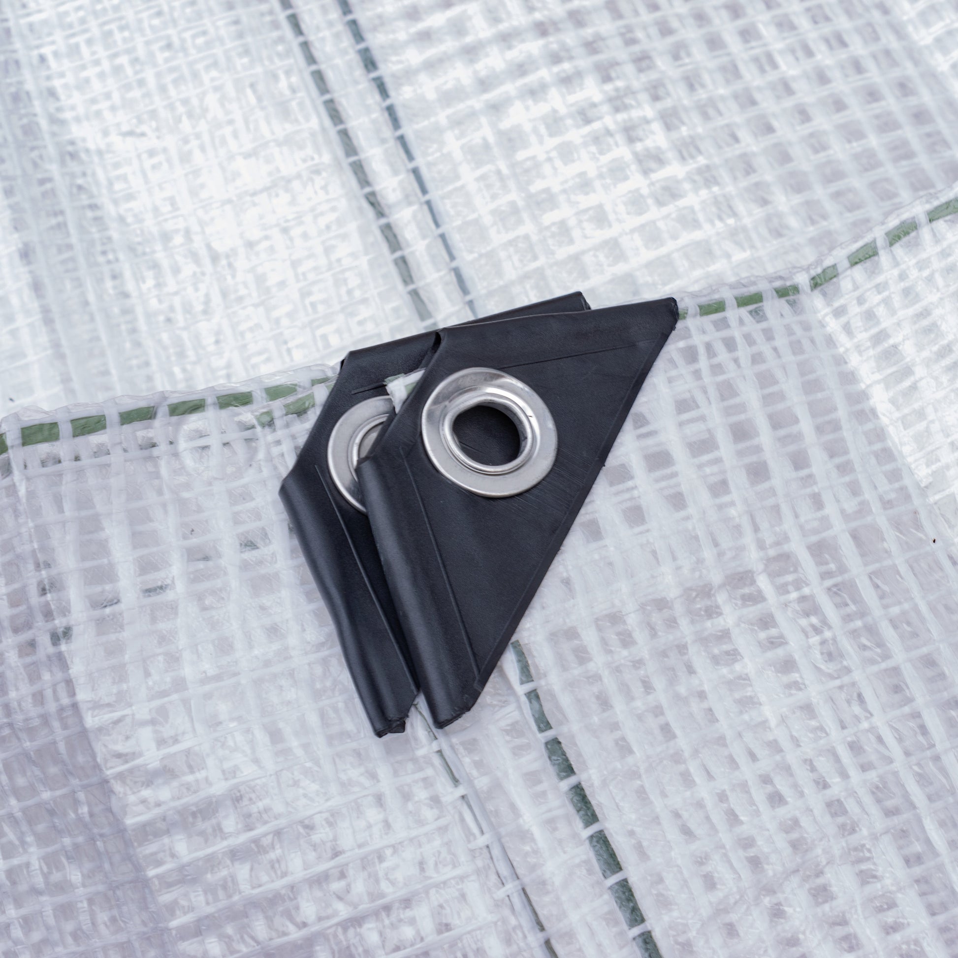 Screw tarp clip attached to clear tarpaulin fabric with metal eyelet