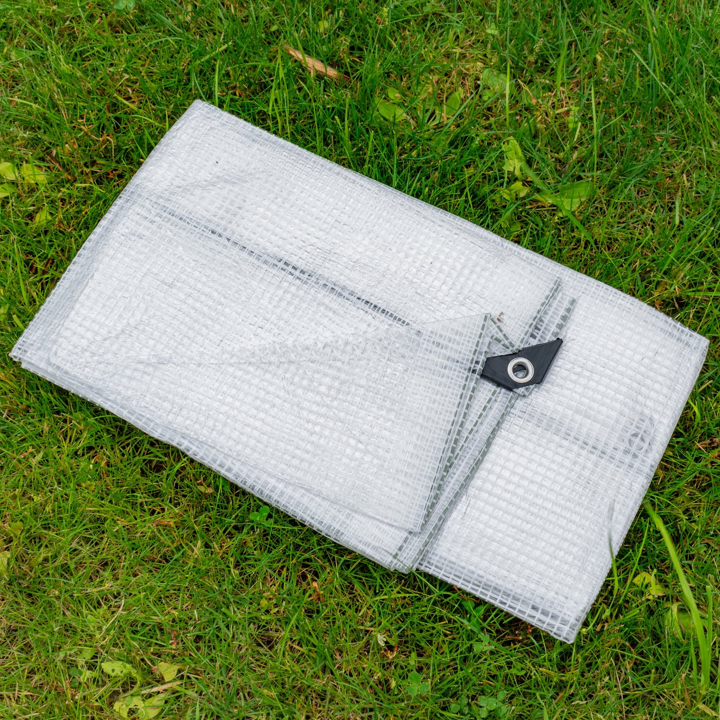Clear tarpaulin with black corner grommet tab and eyelet on transparent mesh