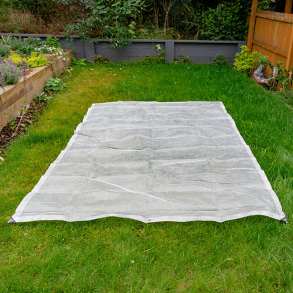 Clear XL tarpaulin spread out flat on grass, with grommet corner points