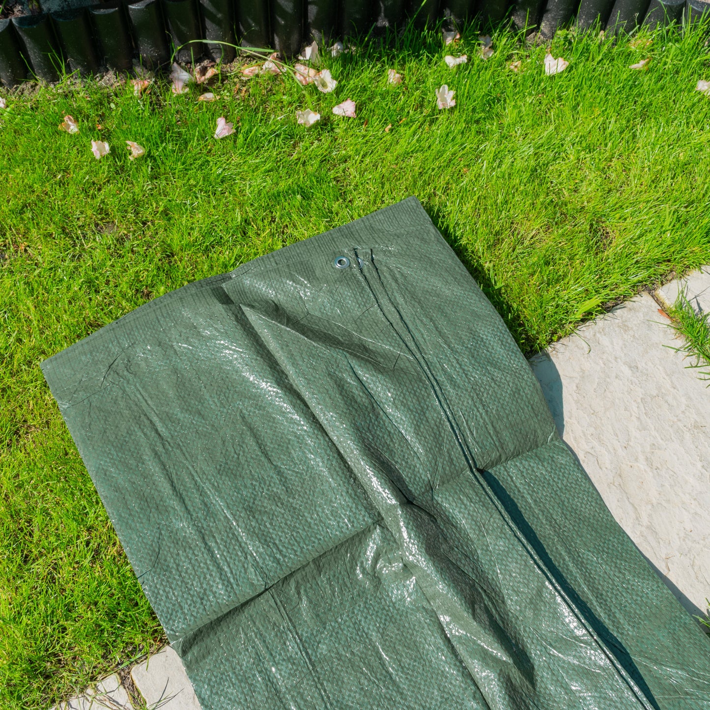 Green tarpaulin sheet, folded, with metal grommets for tying down