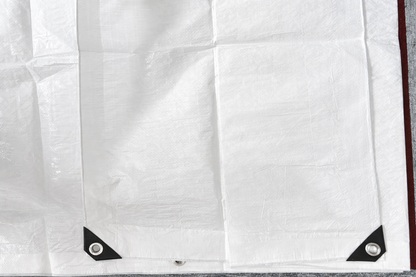 White tarpaulin sheet with black corner patches and metal grommets