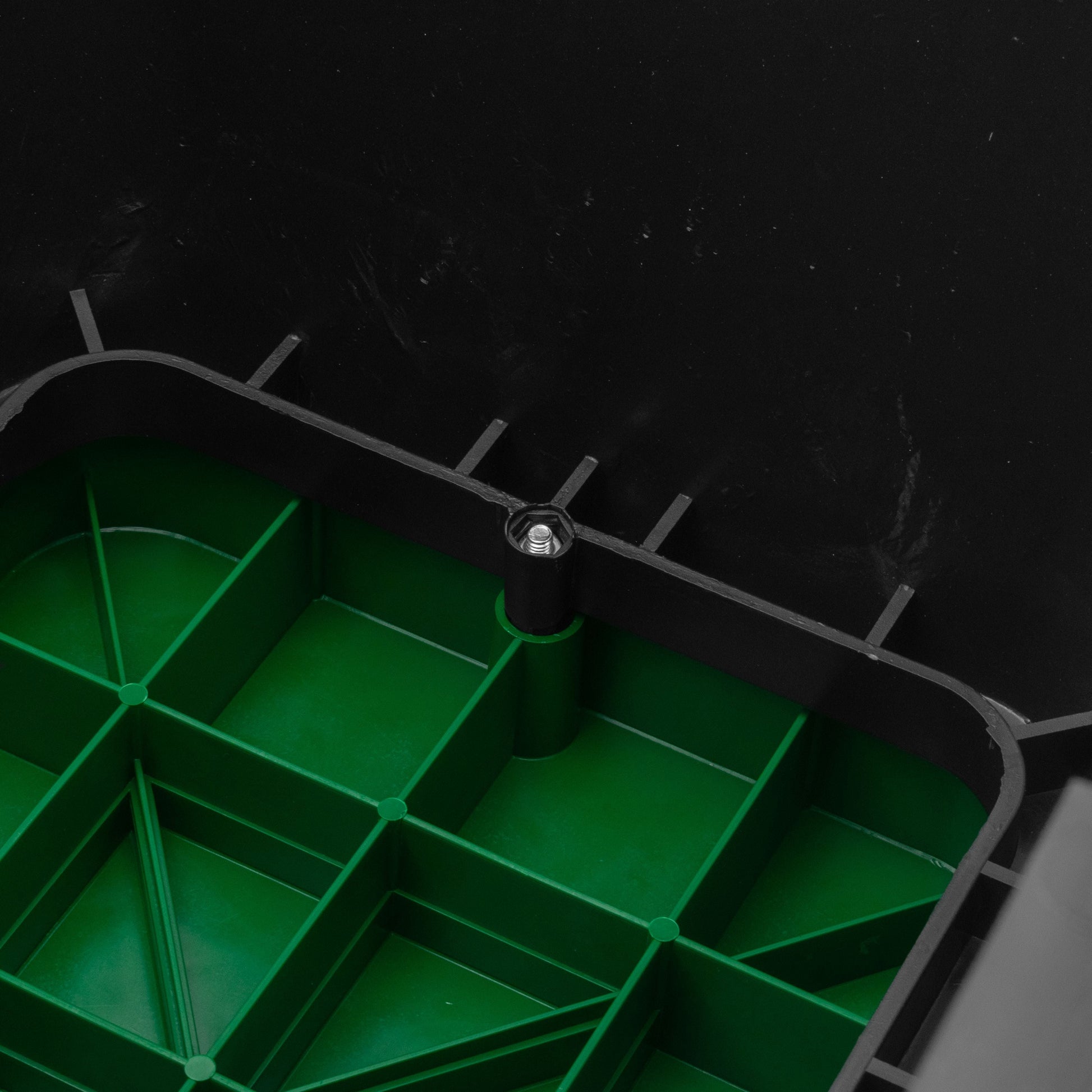 Close-up of green valve box grid and central fastening point inside black housing
