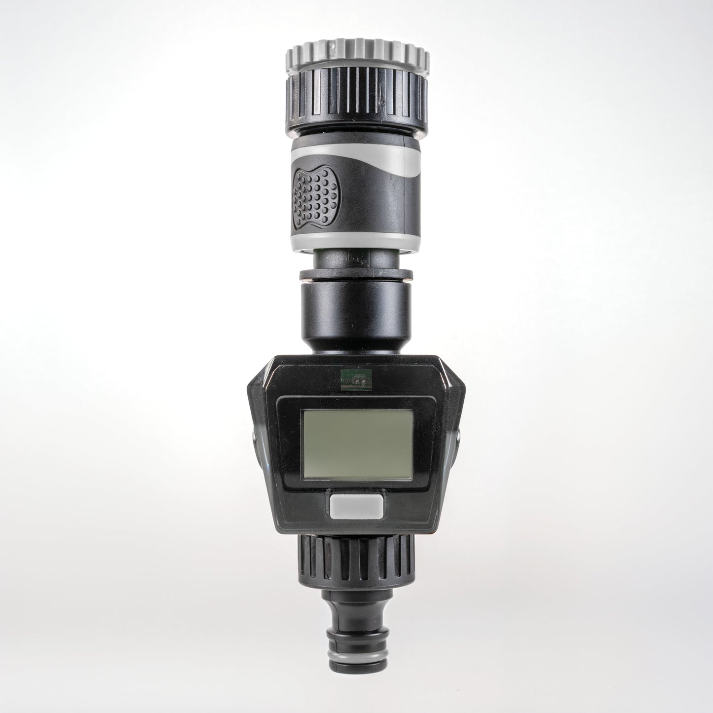 Gray water flow meter with LCD screen, silver ribbed top, and bottom hose connector