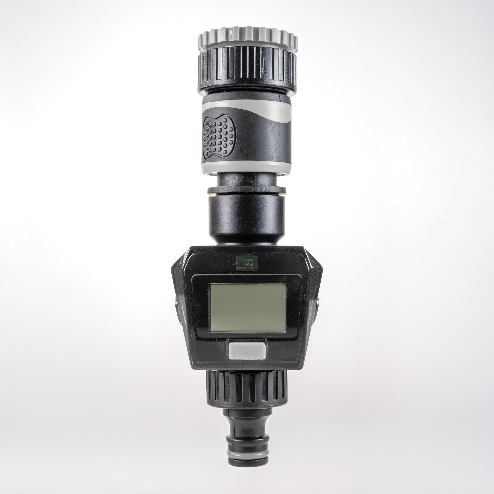 Gray water flow meter with LCD screen, silver ribbed top, and bottom hose connector