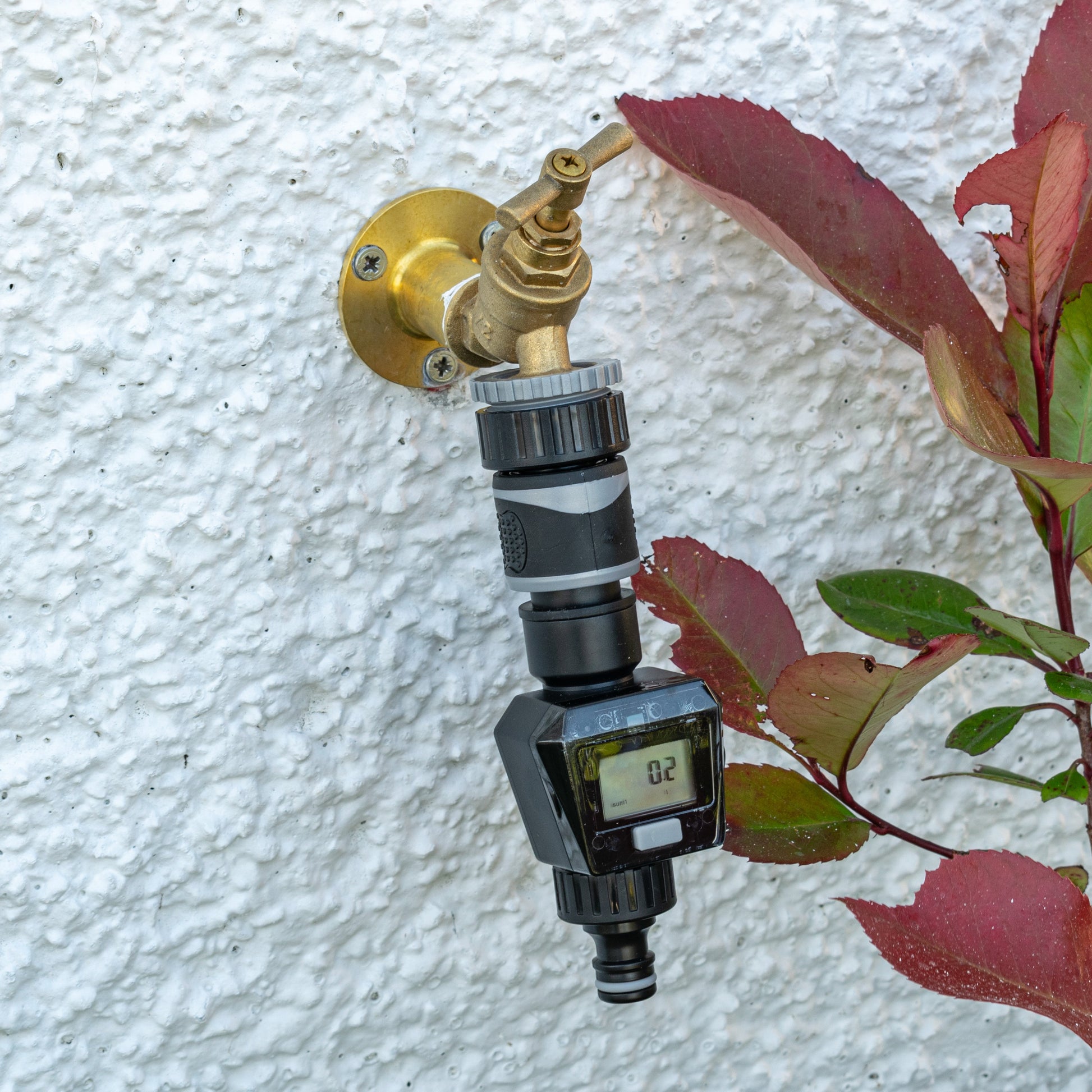 Gray water flow meter on a wall tap with brass valve and LCD reading