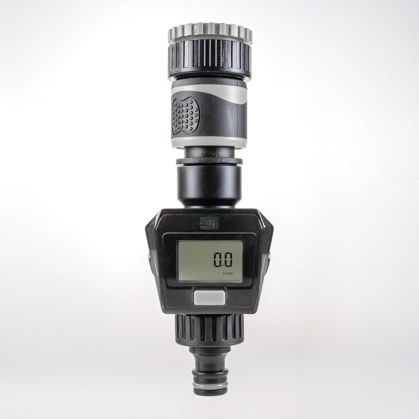 Gray water flow meter close-up showing LCD digits and gray plastic housing