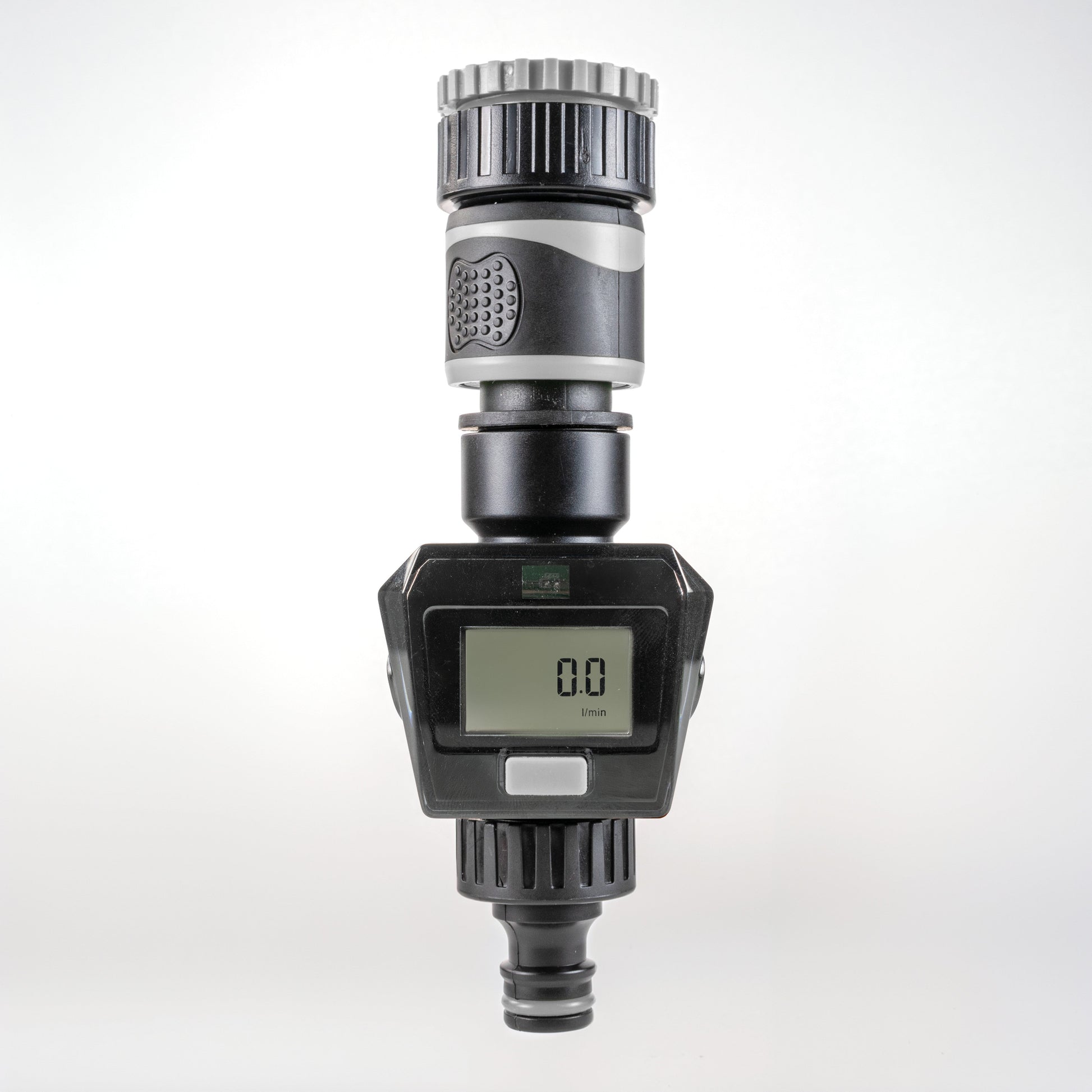 Gray water flow meter close-up showing LCD digits and gray plastic housing