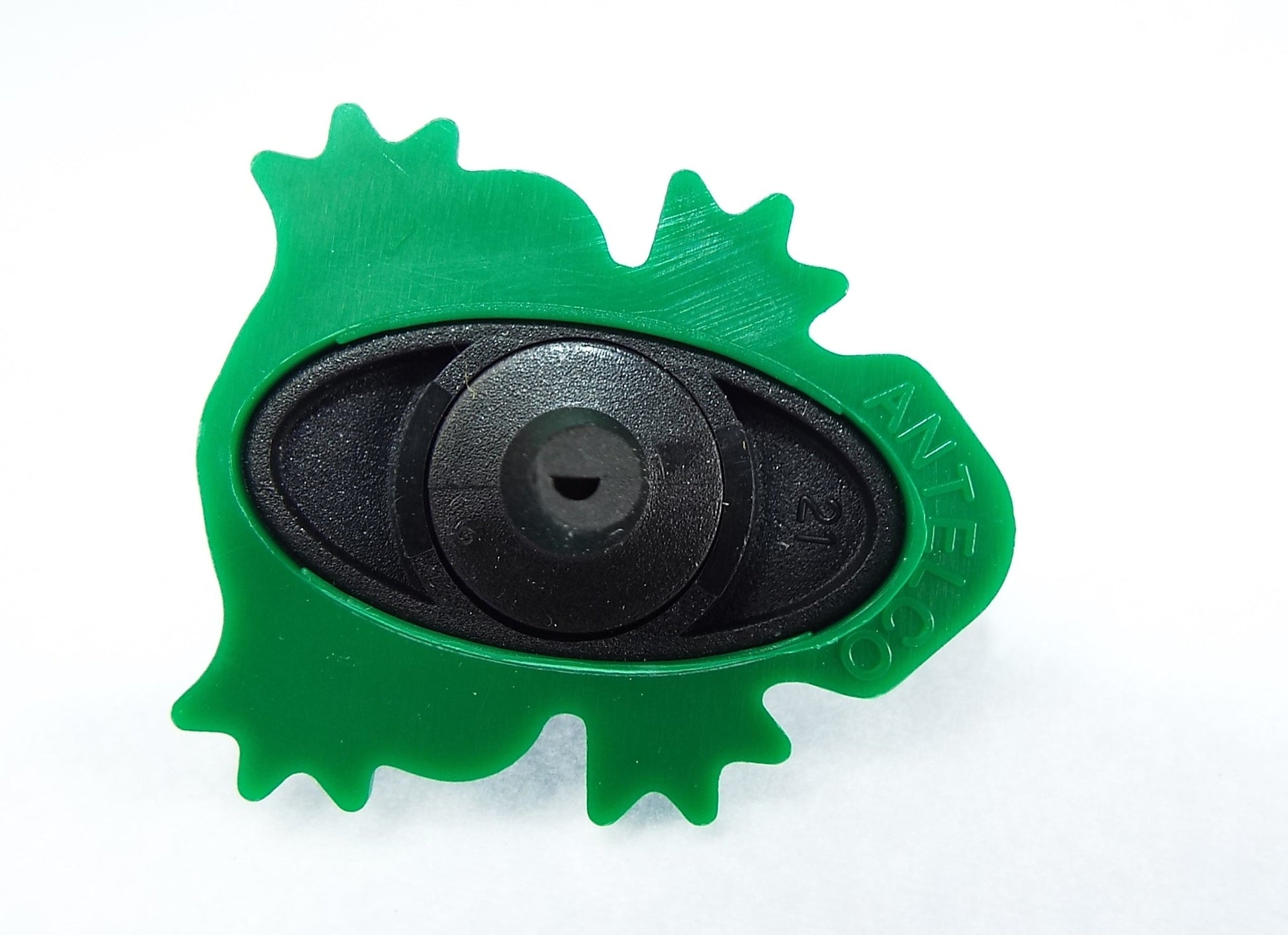 Black circular drip valve insert inside green frog-shaped housing