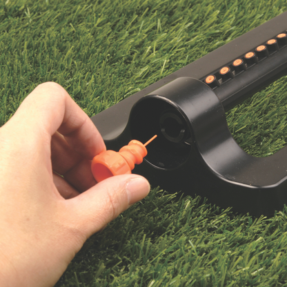 Orange cleaning tool tip connected at the sprinkler outlet on grass