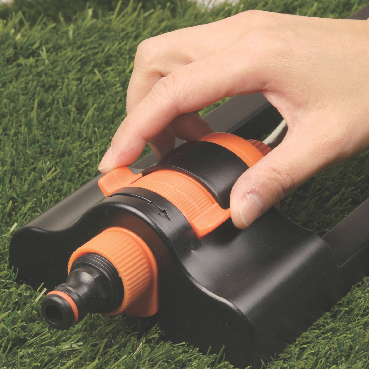 Close-up adjusting the orange control dial on an oscillating sprinkler head