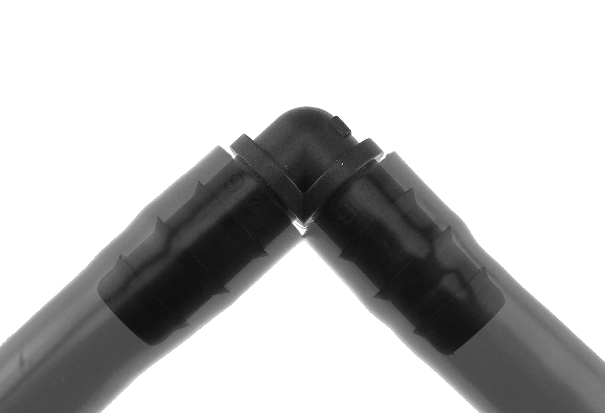 Close-up of black 1/2" irrigation elbow fitting, barbed joint and ridged connectors