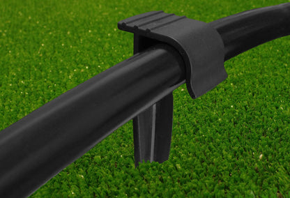 Black stake clip gripping a 16mm irrigation pipe from above