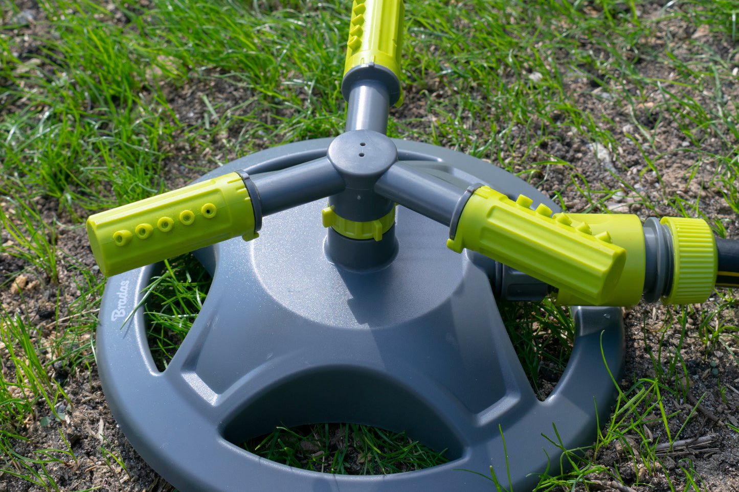 Close-up of 3-arm rotating sprinkler head, lime green arms and gray central hub