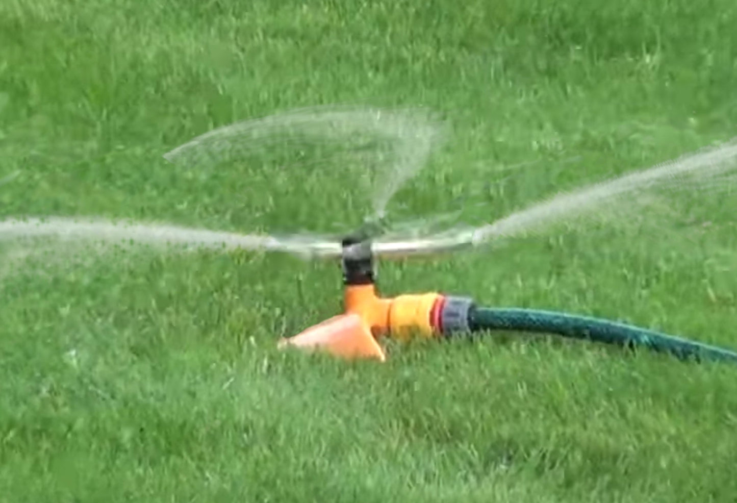 Sprühstrahl aus orangefarbenem 3-Arm-Rotationssprinkler mit Schlauchanschluss
