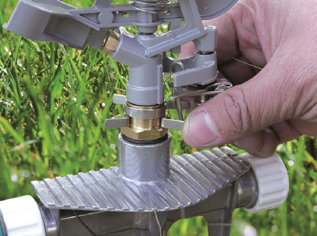 Hand adjusting the pulsating lawn sprinkler’s control ring and nozzle
